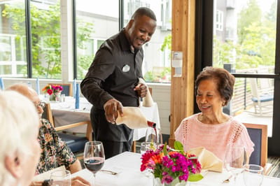 Staff serving wine to a resident in the dining room