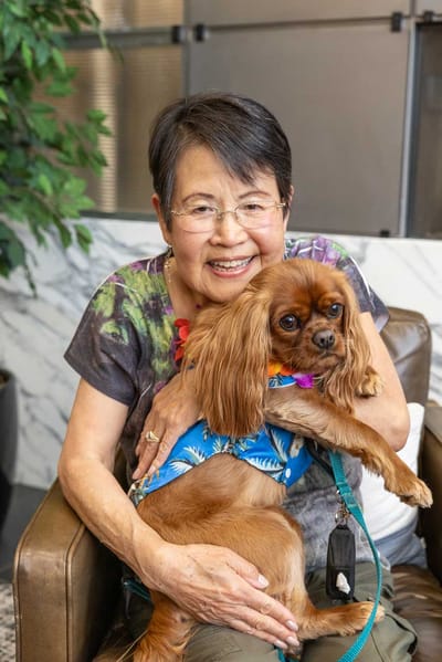 Resident holding a small dog in a cozy lounge area