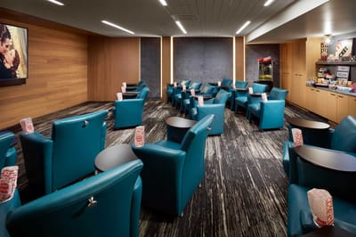 Common lounge area with teal chairs and a large screen