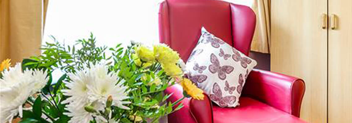 A cozy red chair with decorative pillows and flowers