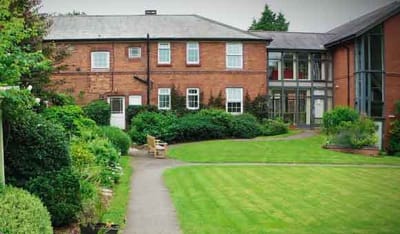 Exterior view of a care home with garden and pathways