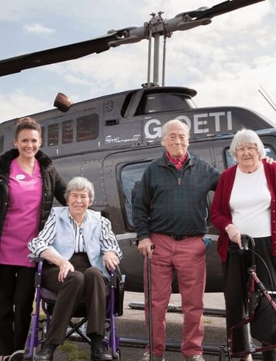 Residents and staff posing with a helicopter