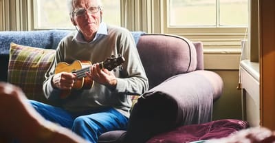 Senior man playing ukulele in a cozy lounge