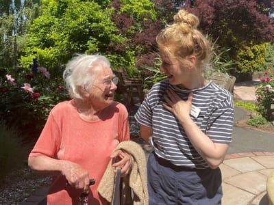 Elderly resident and staff member enjoying a conversation outdoors