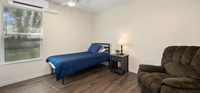 A private resident room with a bed and chair