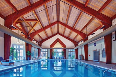 Indoor swimming pool with wooden beams and large windows