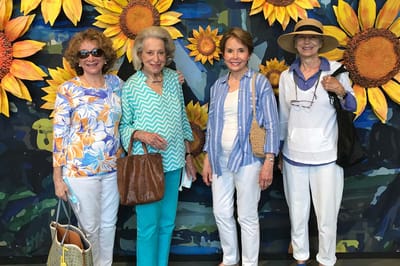 Four women posing in front of sunflower decorations