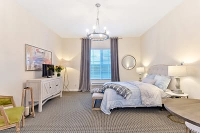 Well-decorated private resident room with a bed and TV