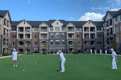 Residents playing croquet on a grassy lawn
