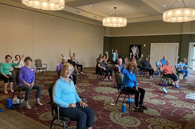 Residents participating in a seated exercise class indoors