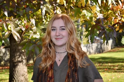 A staff member smiling outside in a garden