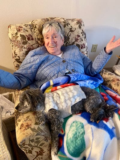 Resident in a chair with a dog, showing affection