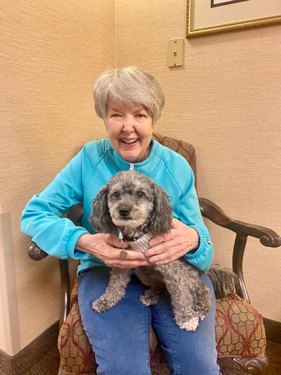A resident smiling and holding a small dog