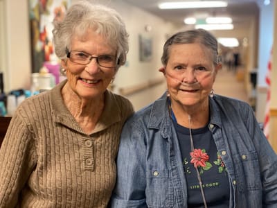 Two smiling senior women in a hallway