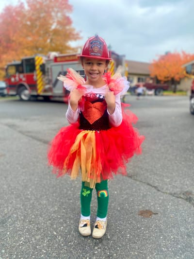 A child in a colorful costume holding pom-poms