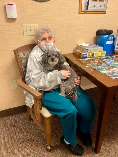 Resident with a small dog in a cozy common area
