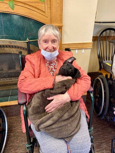 Resident holding a dog, smiling warmly