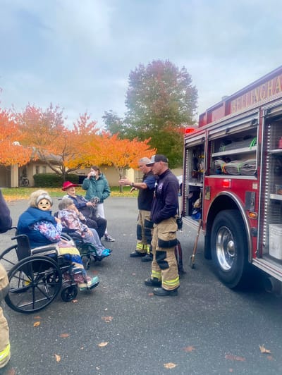Residents interacting with firefighters outside in autumn
