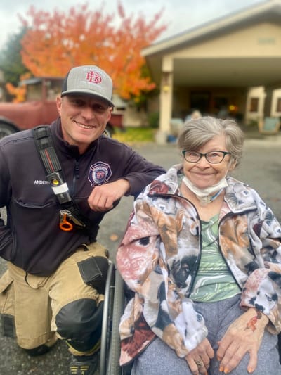 A resident and staff member smiling outdoors at the facility