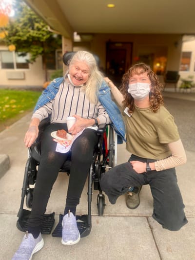 Resident and staff member smiling outdoors