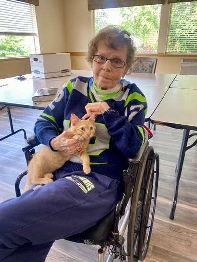 Resident in a wheelchair holding a cat indoors