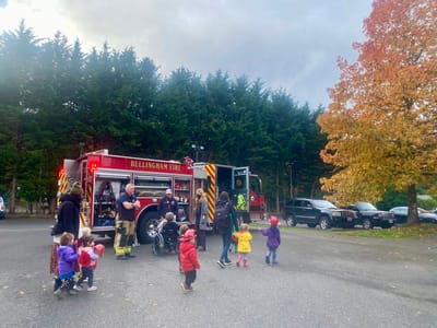 Children interacting with firefighters next to a fire truck