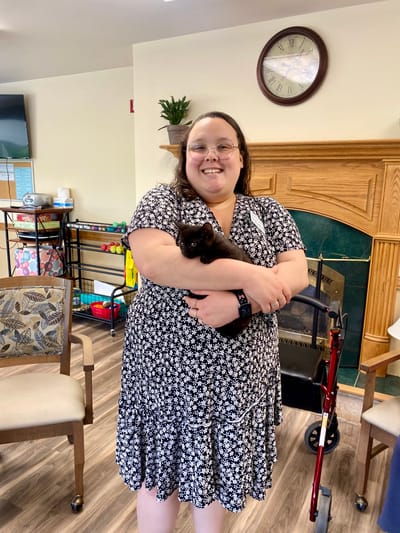 Resident holding a cat in a common area