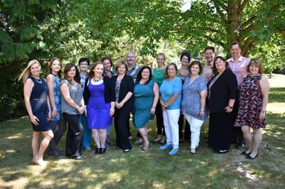 Staff members posing outdoors in a green garden area