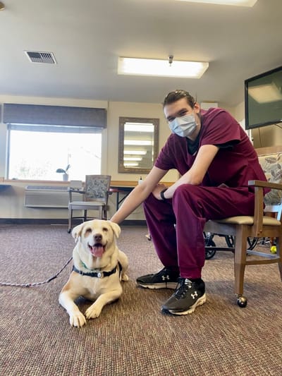 Staff member interact with a therapy dog in a common area