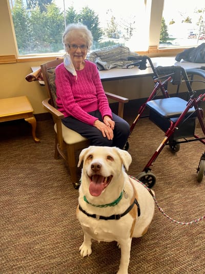 Resident sitting with a dog in a common area