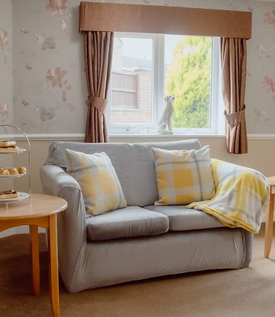 Cozy living room with a sofa and floral wallpaper.