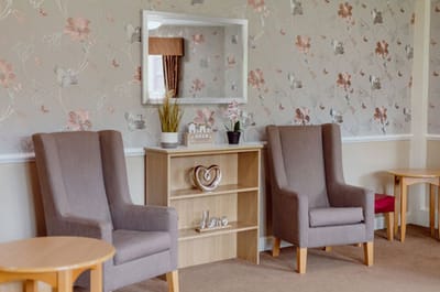 Cozy common area with chairs and floral wallpaper.