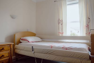 A private resident bedroom with a bed and bedside table.