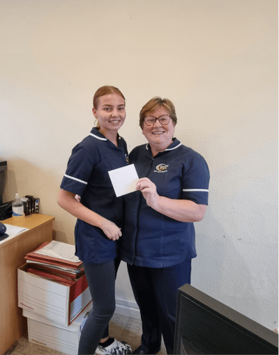 Two staff members holding a card inside the facility.