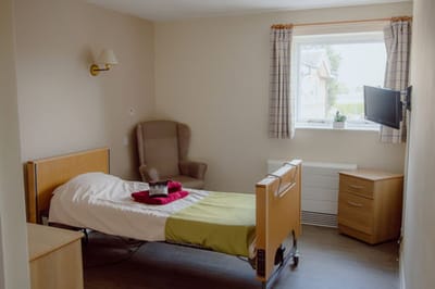 A private resident room with a bed and chair