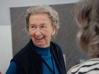 Smiling elderly woman interacting in a common area.