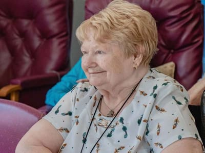 Smiling senior woman in common area seating.