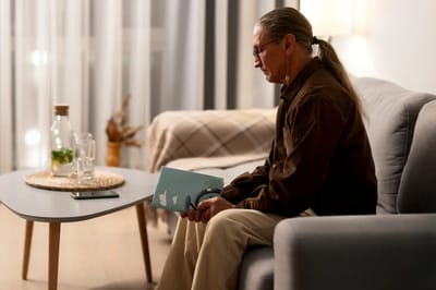 Individual reading a book in a cozy living space.