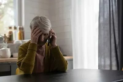 Senior woman on phone looking distressed.