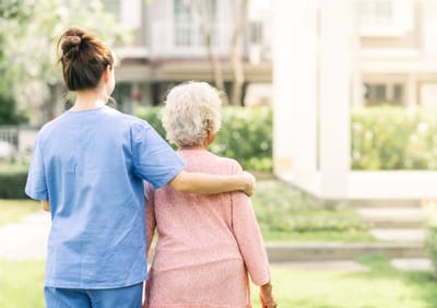 Cedar Court Care Home, memory care in Peterborough, UK — Caregiver walking with elderly resident in a garden