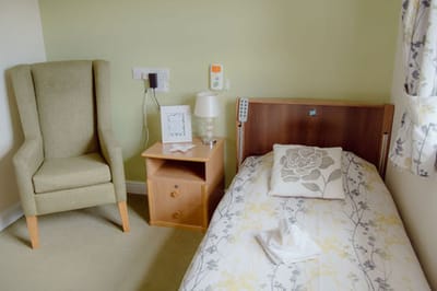 Cozy resident room with a bed and chair.