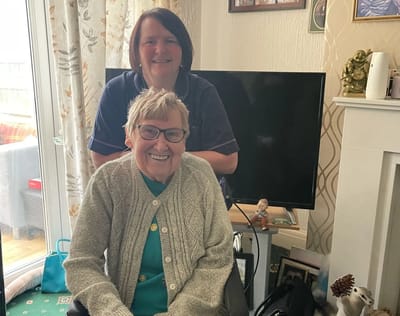 A staff member and a resident smiling indoors.