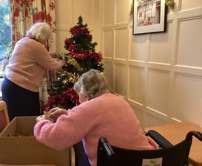 Residents decorating a Christmas tree together.