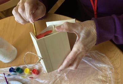 Resident painting a wooden craft project.