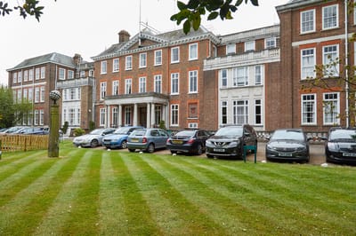 Exterior view of Woodside House with parked cars.
