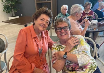 Two women smiling together in a common area