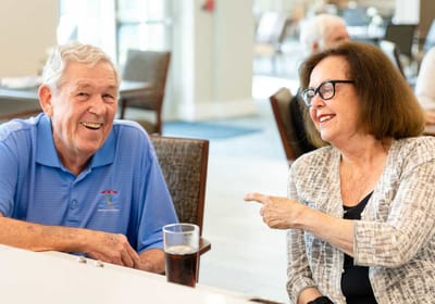 Two seniors laughing and talking in a common area.