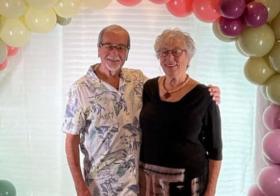 Two residents posing under a balloon arch