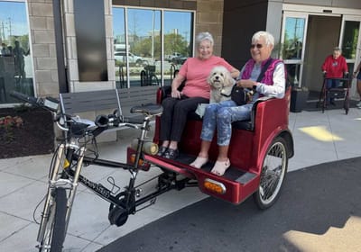 Two seniors enjoying a ride in a bike rickshaw.