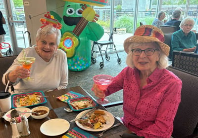 Two residents enjoying drinks and food in a dining area.